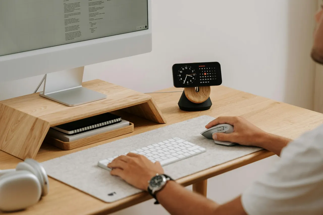 A person sitting at an ergonomically set up desk, looking relaxed and focused, with good posture, bright natural light.